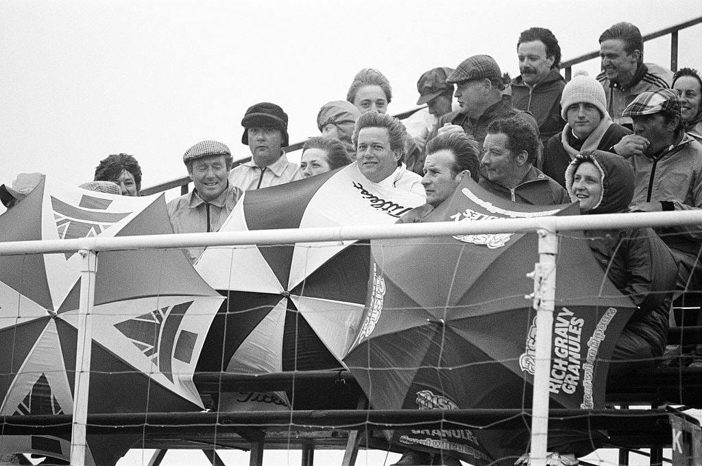 Fans shelter behind umbrellas as a storm hits Muirfield